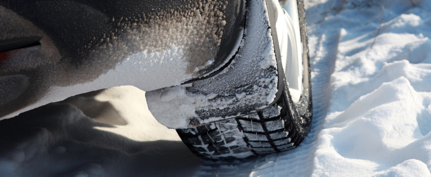 Zoom sur un pneu de voiture qui roule dans la neige
